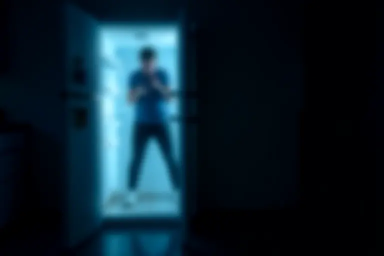 Person looking guiltily at an open fridge at night