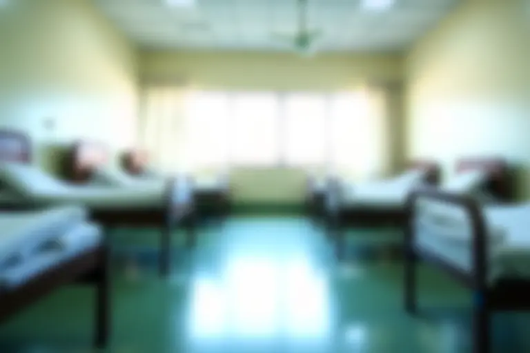 Empty hospital ward with folded mosquito nets on unused beds