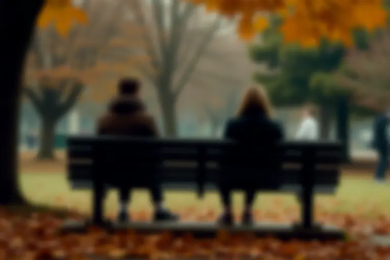 Two people sitting on opposite ends of a park bench looking away from each other