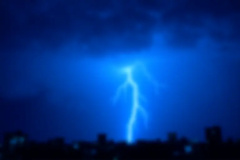 Lightning strike over a city skyline at night
