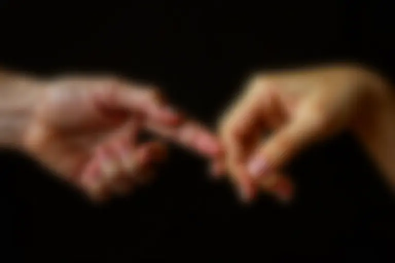 Older and younger hands holding the same worn photograph