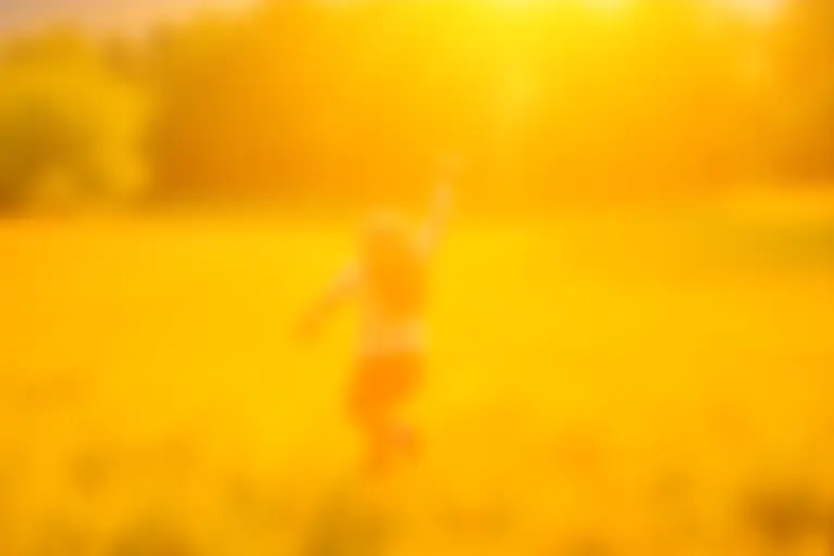 Child playing in a sunlit field with long shadows suggesting a slow afternoon
